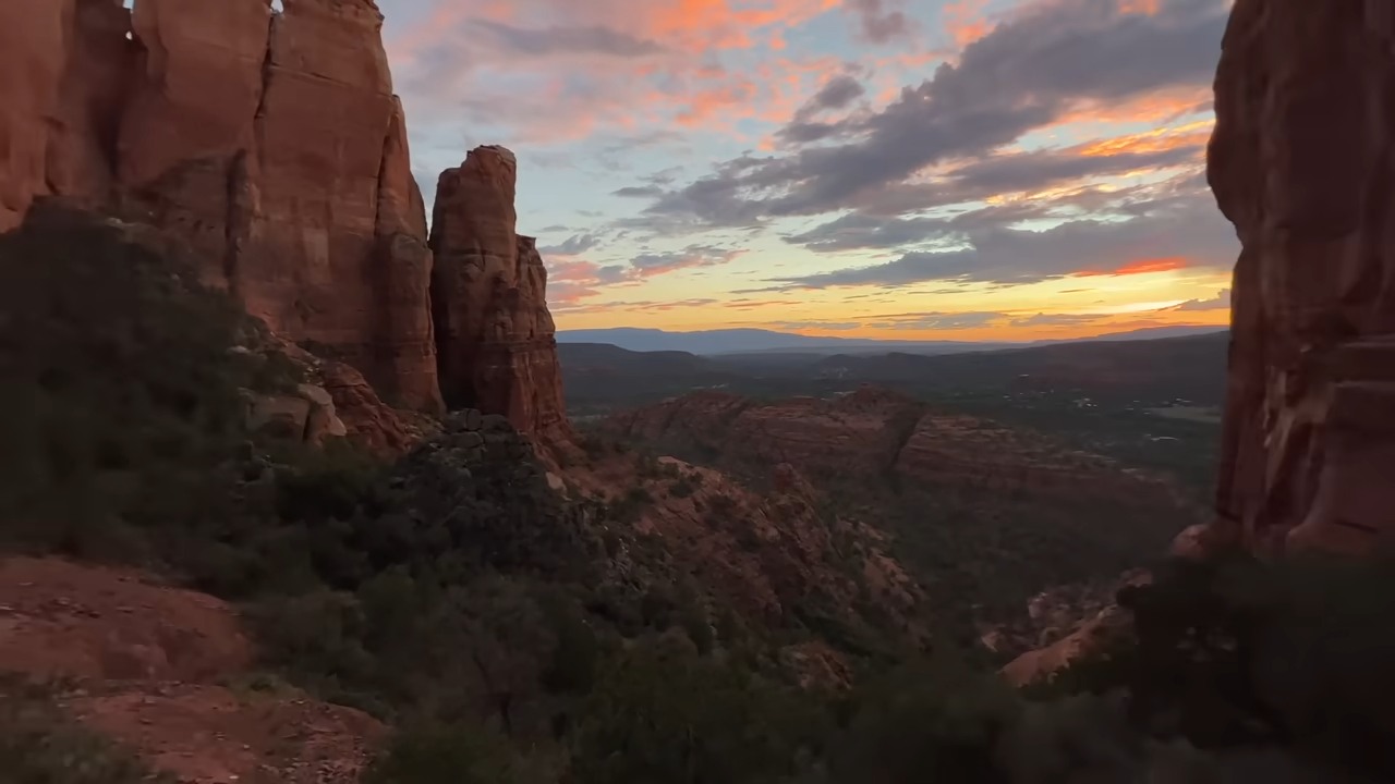 Red sandstone cliffs overlooking Sedona, Arizona, beneath a colorful sunset sky.